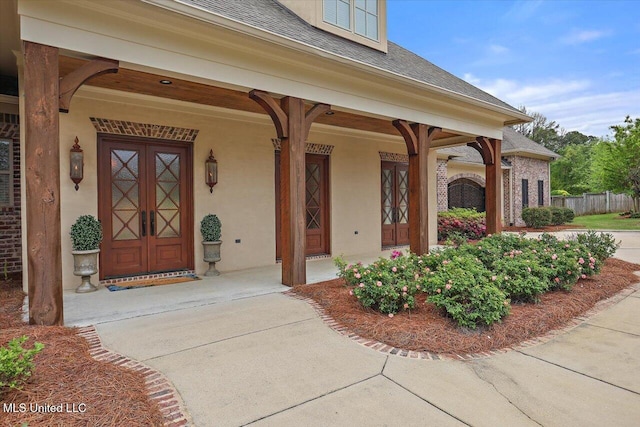 doorway to property with a shingled roof, covered porch, and stucco siding
