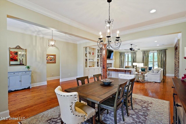dining room featuring baseboards, ceiling fan with notable chandelier, crown molding, and wood finished floors