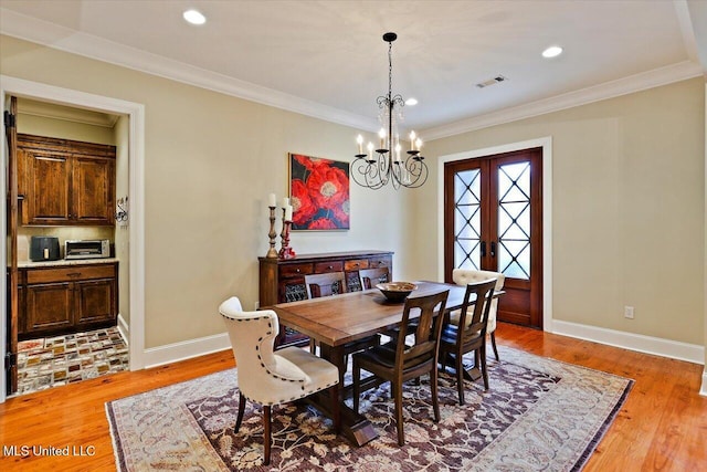 dining space featuring visible vents, an inviting chandelier, light wood-type flooring, crown molding, and french doors