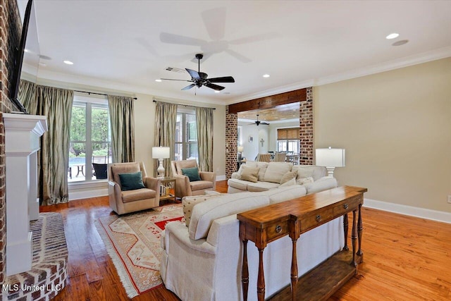 living area with ornamental molding, ceiling fan, hardwood / wood-style floors, and baseboards