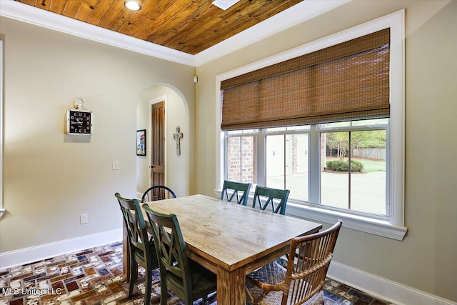 dining space with baseboards, arched walkways, wood ceiling, crown molding, and brick floor