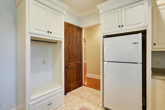 kitchen with ornamental molding, light countertops, white cabinetry, freestanding refrigerator, and light tile patterned flooring