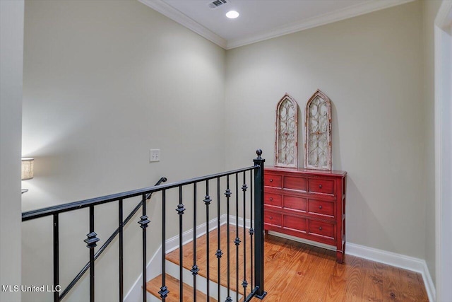 hall featuring visible vents, baseboards, an upstairs landing, crown molding, and wood finished floors