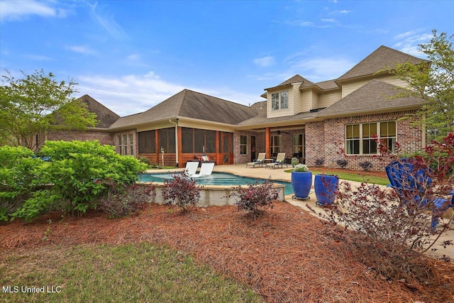 rear view of property featuring a patio, an outdoor pool, a ceiling fan, brick siding, and a sunroom