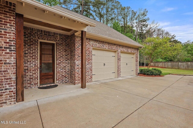 garage with concrete driveway and fence