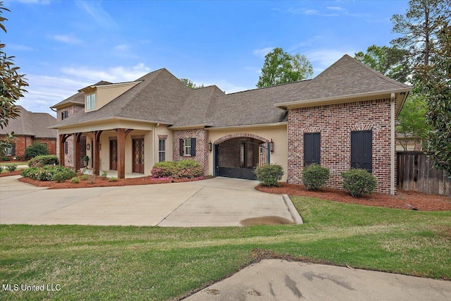 view of front of property featuring stucco siding, a front lawn, brick siding, fence, and a shingled roof