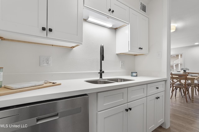 kitchen featuring hardwood / wood-style flooring, dishwasher, sink, and white cabinets