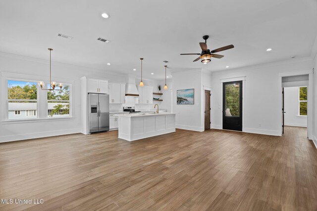 unfurnished living room with light hardwood / wood-style floors, crown molding, a healthy amount of sunlight, and sink