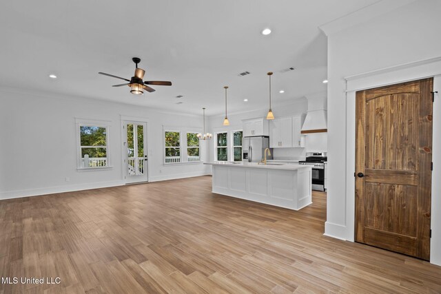 unfurnished living room featuring sink, ornamental molding, light hardwood / wood-style flooring, and ceiling fan with notable chandelier