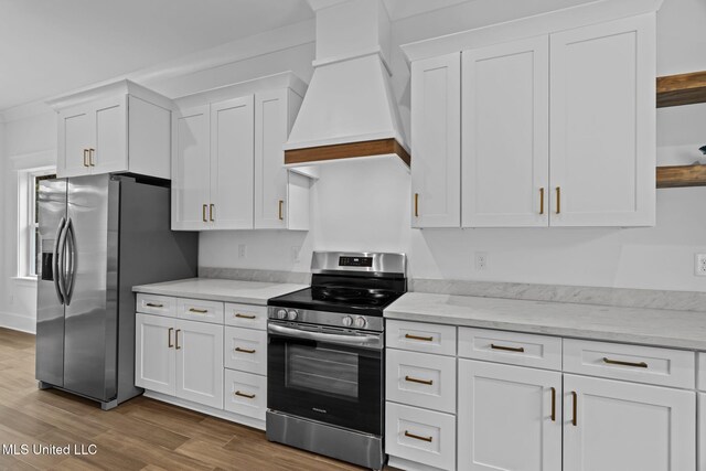 kitchen with white cabinets, light stone countertops, wood-type flooring, custom range hood, and stainless steel appliances