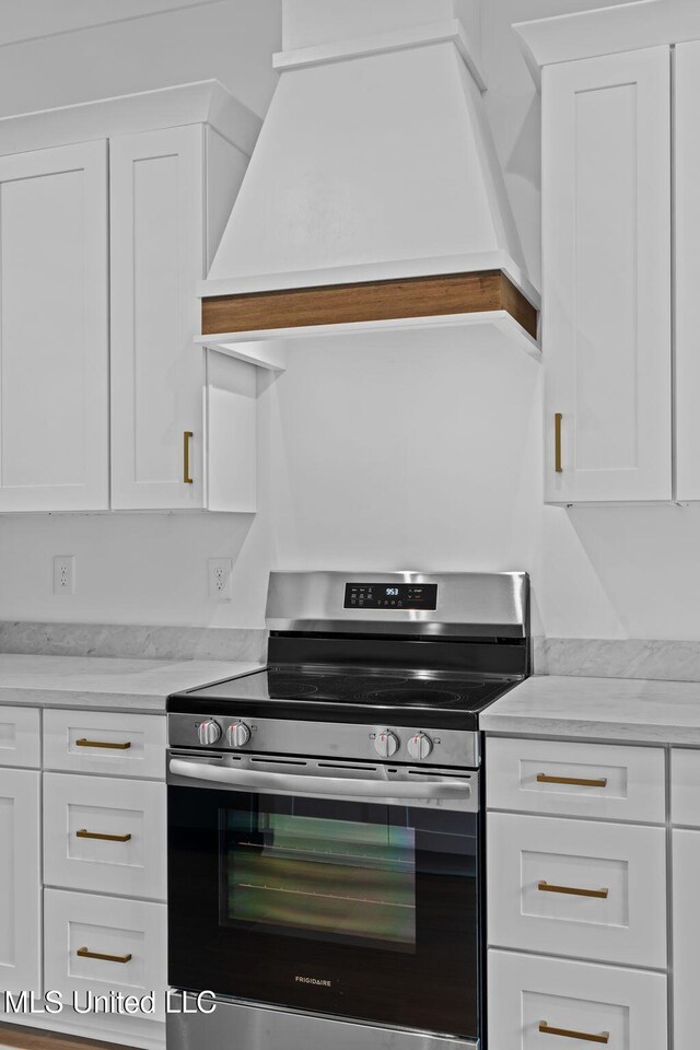 kitchen featuring stainless steel range oven and white cabinets