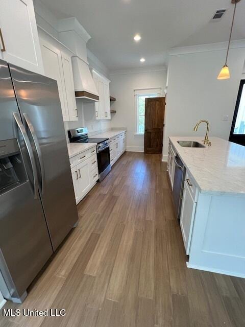 kitchen with hanging light fixtures, white cabinetry, custom range hood, sink, and stainless steel appliances