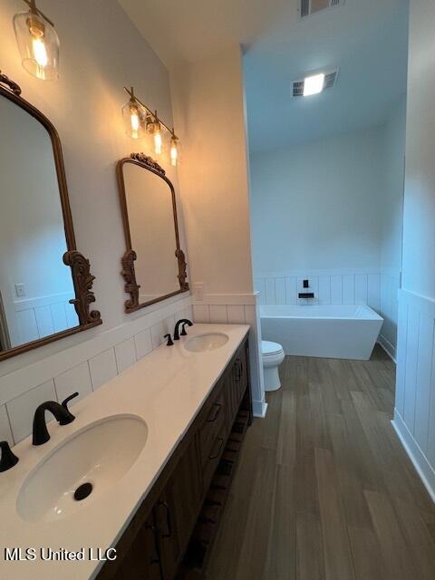 bathroom featuring toilet, a tub, vanity, and wood-type flooring