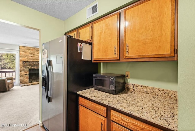 221 Highpoint Dr, Diamondhead, MS 39525 - kitchen with light stone countertops, a fireplace, a textured ceiling, light colored carpet, and stainless steel fridge with ice dispenser