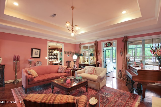 living room with dark tile patterned flooring, ornamental molding, a chandelier, and a raised ceiling