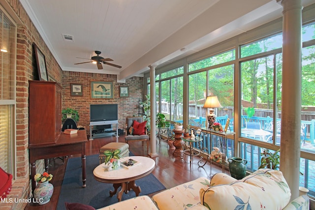 living room featuring decorative columns, hardwood / wood-style flooring, brick wall, and a wealth of natural light