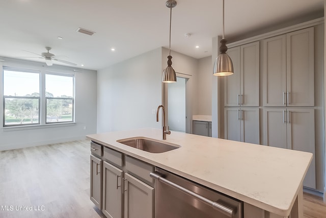 kitchen with sink, an island with sink, light hardwood / wood-style floors, decorative light fixtures, and stainless steel dishwasher