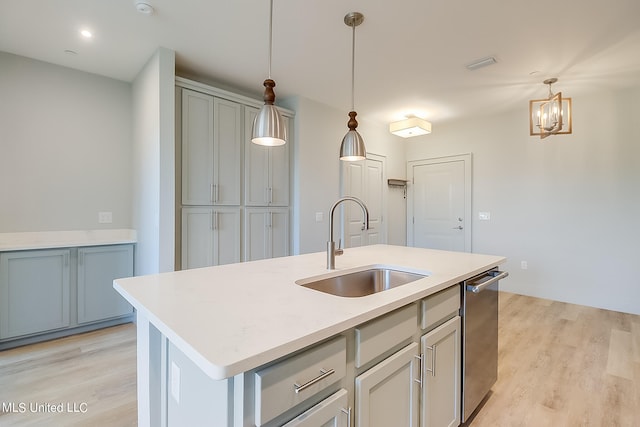 kitchen featuring light hardwood / wood-style floors, sink, decorative light fixtures, and a center island with sink