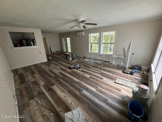 living room featuring a textured ceiling, a wall mounted AC, wood-type flooring, and ceiling fan