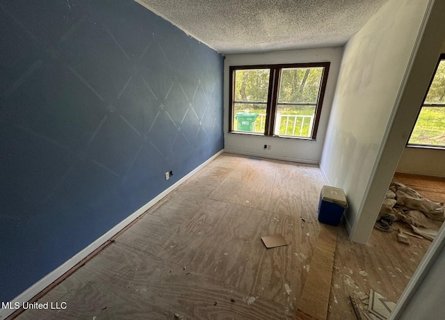 unfurnished room featuring a textured ceiling and a healthy amount of sunlight