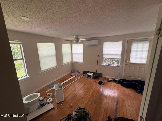 spare room featuring an AC wall unit, a textured ceiling, hardwood / wood-style flooring, and ceiling fan