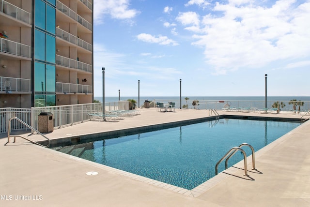 view of swimming pool featuring a water view and a patio