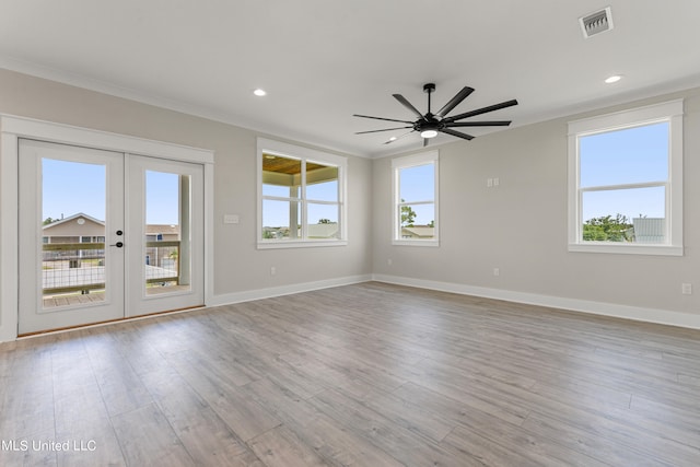 spare room with crown molding, french doors, a healthy amount of sunlight, and light wood-type flooring