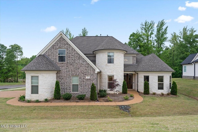 french country inspired facade with stone siding, roof with shingles, and a front lawn
