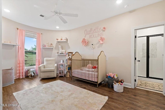 bedroom with a crib, visible vents, wood finished floors, and baseboards