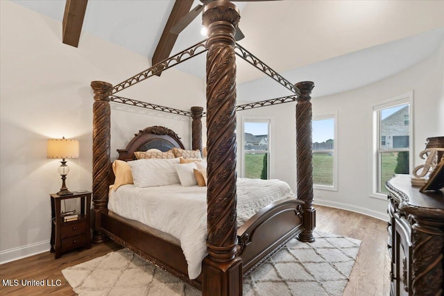 bedroom featuring baseboards, lofted ceiling with beams, and wood finished floors