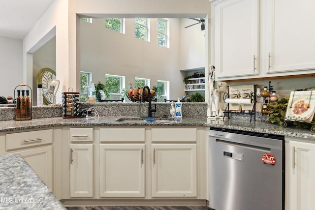 kitchen with a sink, light stone counters, dishwasher, a ceiling fan, and white cabinets