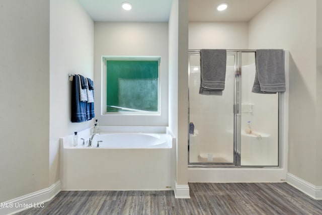 full bath featuring a stall shower, baseboards, a garden tub, and wood finished floors