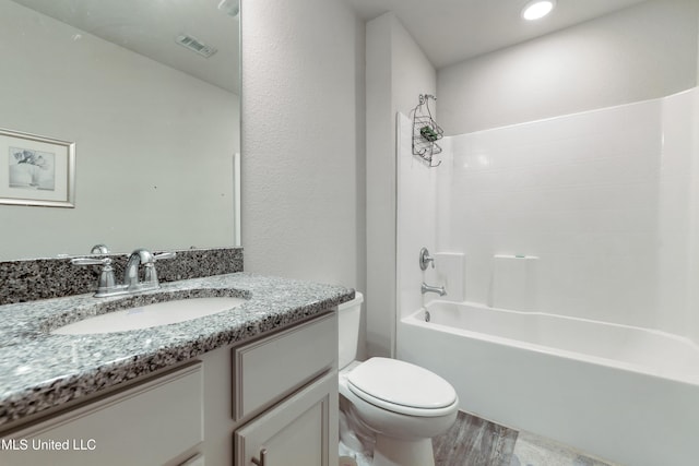 full bathroom featuring toilet, visible vents, vanity, wood finished floors, and washtub / shower combination