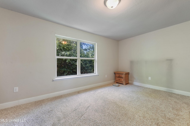 carpeted empty room featuring baseboards