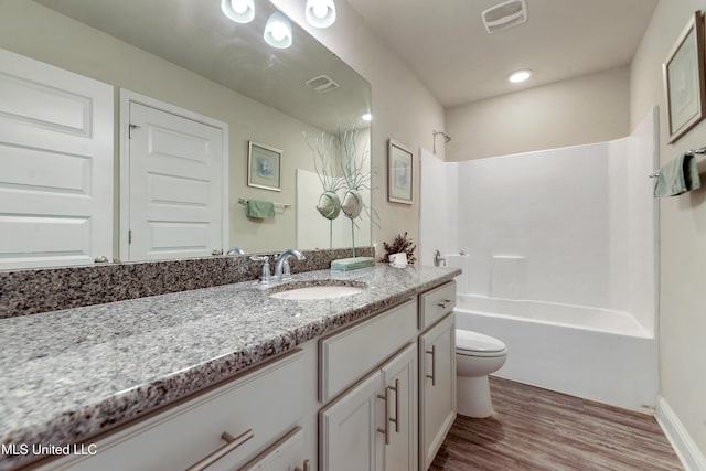 bathroom featuring toilet, shower / washtub combination, wood finished floors, vanity, and visible vents