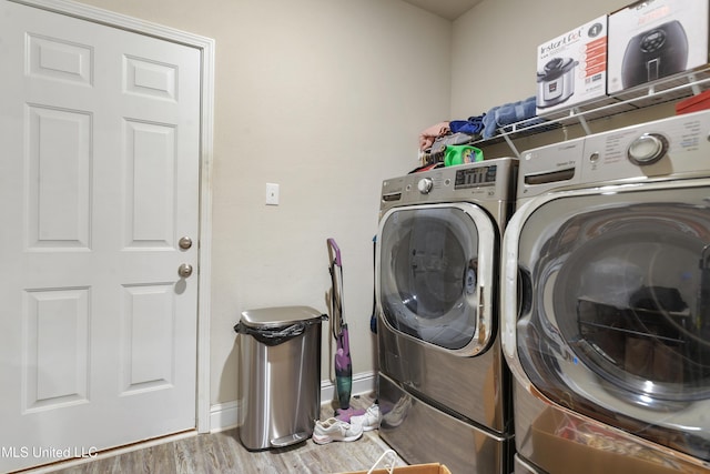 clothes washing area featuring laundry area, wood finished floors, baseboards, and washer and dryer