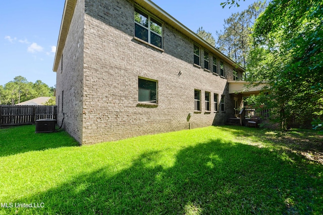 rear view of house featuring a yard, fence, and brick siding