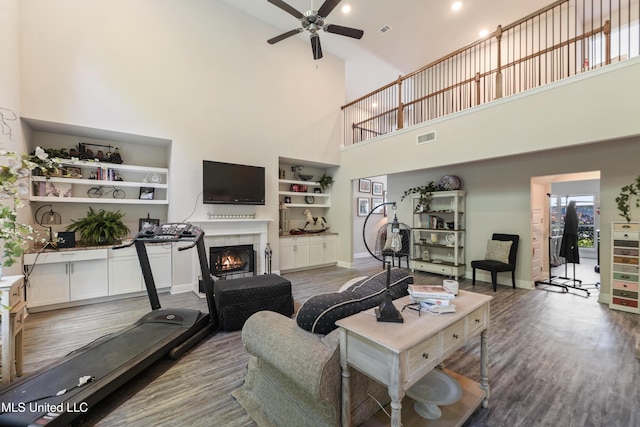 living room featuring visible vents, wood finished floors, a towering ceiling, and ceiling fan