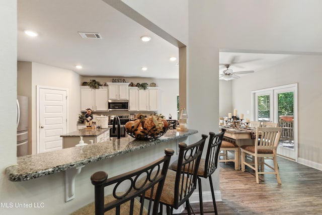 kitchen featuring stone countertops, stainless steel appliances, visible vents, recessed lighting, and dark wood-style flooring