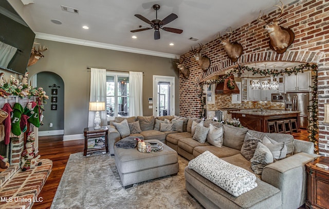 living room with crown molding, ceiling fan, brick wall, and dark hardwood / wood-style floors