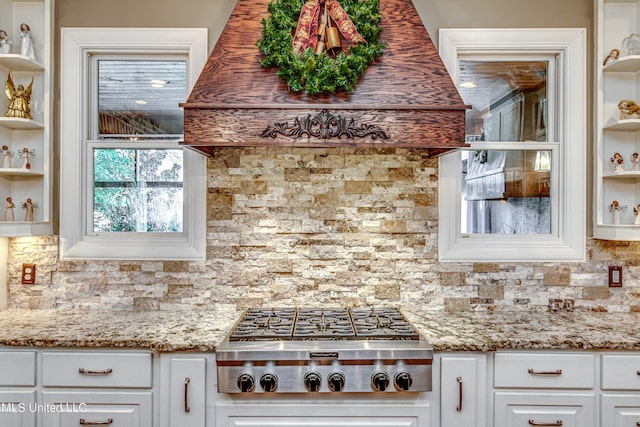 kitchen with tasteful backsplash, light stone counters, stainless steel gas stovetop, and white cabinetry