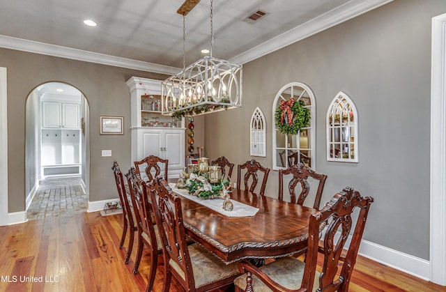 dining room featuring an inviting chandelier, ornamental molding, and light wood-type flooring