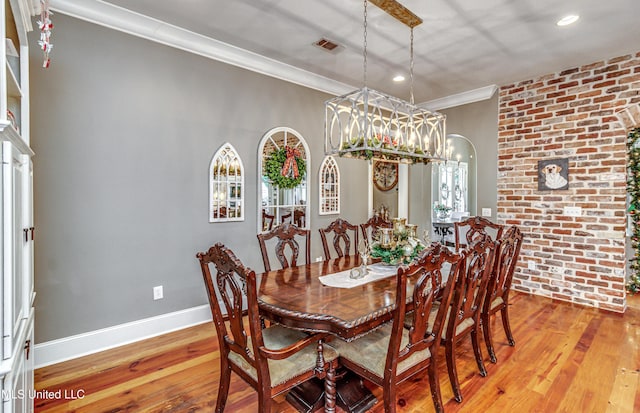 dining space with crown molding, an inviting chandelier, and light wood-type flooring