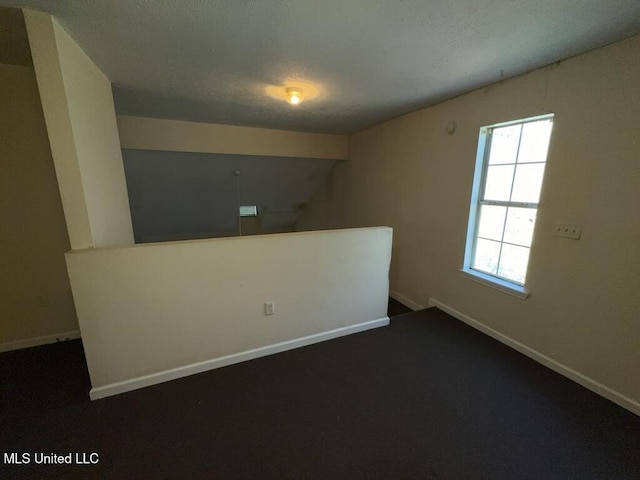 empty room featuring a textured ceiling and baseboards