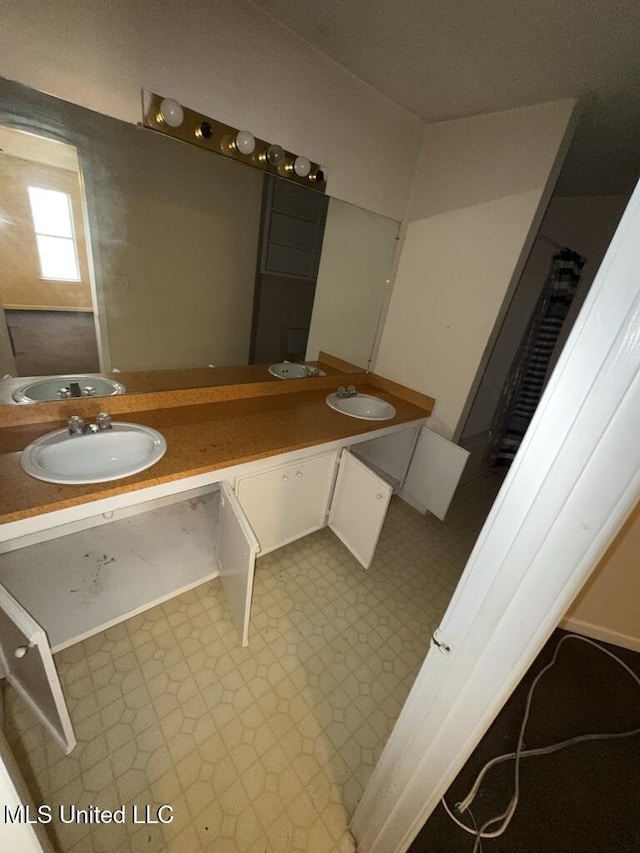 full bathroom with double vanity, a sink, and tile patterned floors