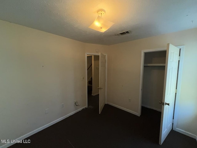 unfurnished bedroom featuring baseboards, a closet, visible vents, and a textured ceiling