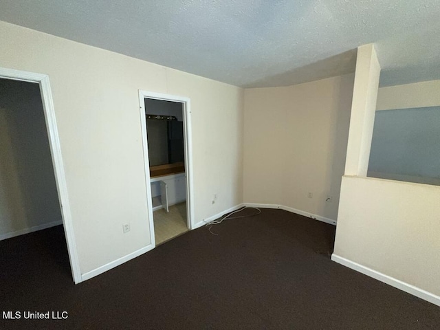 empty room with a textured ceiling, carpet, and baseboards