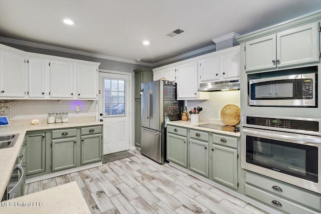 5751 Orchardview Dr, Jackson, MS 39211 - kitchen with appliances with stainless steel finishes, crown molding, tasteful backsplash, under cabinet range hood, and light countertops