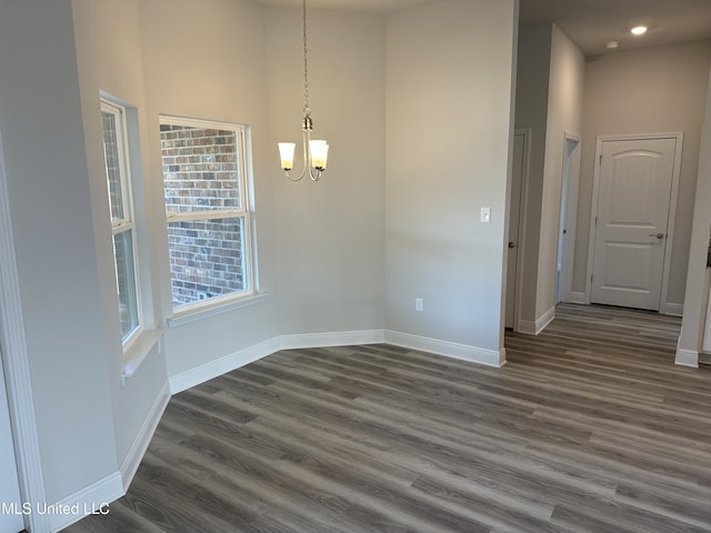 unfurnished dining area with a towering ceiling, dark hardwood / wood-style flooring, and a notable chandelier