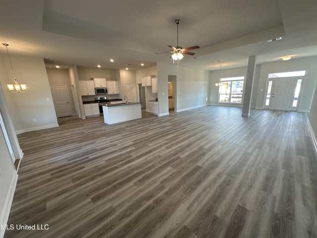 unfurnished living room with dark wood-type flooring and ceiling fan with notable chandelier